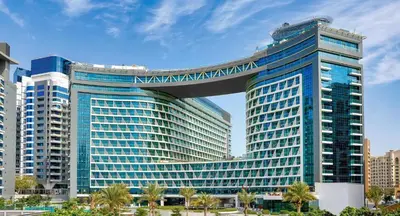 a tall blue building with a bridge over it at Seven Palm Residences - Private Beach Access, Infinity Pool with Sea View in Dubai