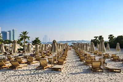 a bunch of chairs and umbrellas on a beach at Seven Palm Residences - Private Beach Access, Infinity Pool with Sea View in Dubai