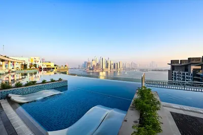 a pool on the roof of a building with a view of the city at Seven Palm Residences - Private Beach Access, Infinity Pool with Sea View in Dubai