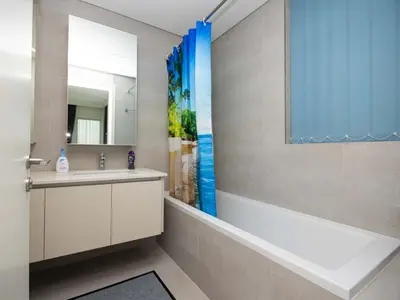 a bathroom with a tub and a sink and a mirror at Beach View family friendly unit in Dubai in Dubai