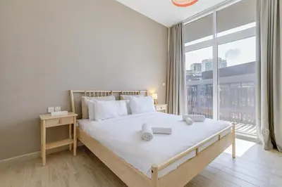 a bedroom with a bed with a large window at Stylish 2BR Apartment in Belgravia III A, JVC - Allsopp & Allsopp in Dubai