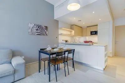 a kitchen and living room with a table and chairs at Stylish 2BR Apartment in Belgravia III A, JVC - Allsopp & Allsopp in Dubai