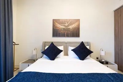 a bedroom with a white bed with blue pillows at Stylish 1BR City View at Vida Creek Beach in Dubai
