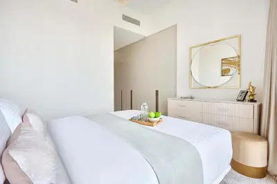 a white bedroom with a white bed and a mirror at Frank Porter - Grande Signature Residence in Dubai