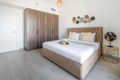 a bedroom with a large bed and a wooden cabinet at Frank Porter - Lamtara 3, MJL in Dubai