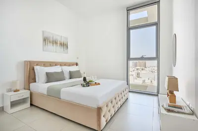 a white bedroom with a large bed and a window at Frank Porter - Pulse Residence Park B3 in Dubai