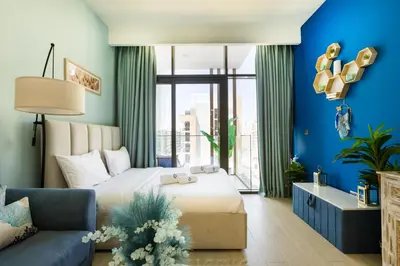 a bedroom with blue walls and a bed and a couch at Modern Elegance in a Cosy Retreat with Balcony - Azizi Riviera in Dubai