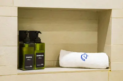 a shelf with two bottles of soap and a towel at Modern Elegance in a Cosy Retreat with Balcony - Azizi Riviera in Dubai