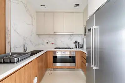 a kitchen with white cabinets and a stainless steel refrigerator at Address Residence Dubai Opera 34 by Luxstay Holiday Homes in Dubai