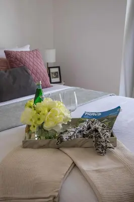 a tray with flowers and a bottle on a bed at Frank Porter - West Avenue in Dubai