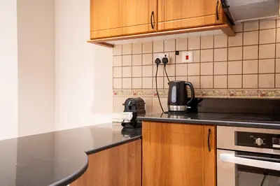 a kitchen with wooden cabinets and a black counter top at Charming 1BR with Sea & City Views in Dubai