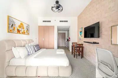 a bedroom with a large white bed and a tv at FIRST CLASS Studio Modern Vibes in Dubai in Dubai