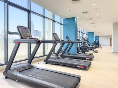 a row of treadmills in a gym with windows at FIRST CLASS Studio Modern Vibes in Dubai in Dubai
