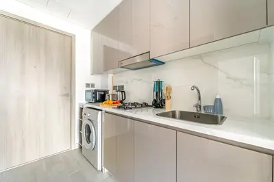a white kitchen with a sink and a dishwasher at FIRST CLASS Studio Modern Vibes in Dubai in Dubai