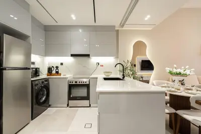 a kitchen with white cabinets and a white counter top at Burj et Canal View Sunny Pool in Dubai