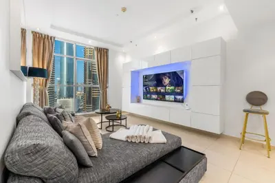 a living room with a couch and a tv at Modern 1BR JBR View No Car Needed! in Dubai