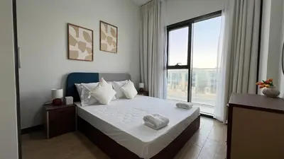 a bedroom with a large bed and a large window at Daraqa - Modern 1BR Apartment in Peaceful Dubai Land in Dubai