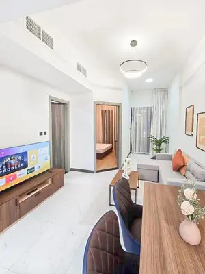 a living room with a couch and a tv at Daraqa - Modern 1BR Apartment in Peaceful Dubai Land in Dubai