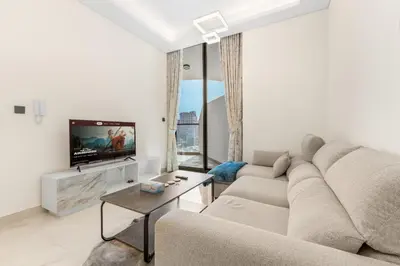 a living room with a couch and a tv at Chic One-Bed Haven w Pool & Gym Heart of Dubai in Dubai