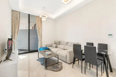 a living room with a couch and a table and chairs at Chic One-Bed Haven w Pool & Gym Heart of Dubai in Dubai