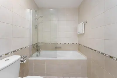 a white bathroom with a tub and a toilet at Exquisite 2-Bedroom with Panoramic Marina view in Dubai
