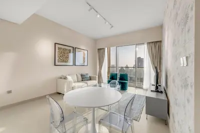 a white living room with a white table and chairs at Skyline View, Stay High Rise Luxury next to Burj in Dubai