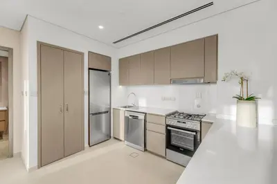a kitchen with stainless steel appliances and wooden cabinets at Skyline View, Stay High Rise Luxury next to Burj in Dubai