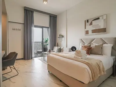 a bedroom with a large bed and a living room at Welhome - Chic Studio with Balcony & City Views in Dubai in Dubai