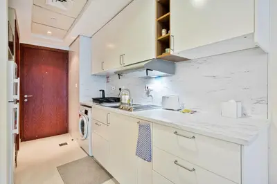 a white kitchen with a sink and a stove at Comfy Studio with Views Near Marina & Burj Al in Dubai