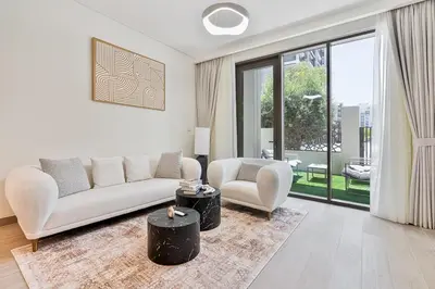 a white living room with a couch and a table at Vibrant 1BR With Airy Patio, Beach, Pool and Gym Access in Dubai