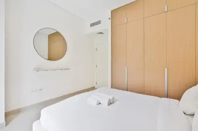 a bedroom with a white bed and a mirror at Vibrant 1BR With Airy Patio, Beach, Pool and Gym Access in Dubai