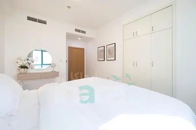a white bedroom with a large bed and a mirror at Luxury 1 Br Marina Near Tram Ain Sea View Balcony in Dubai
