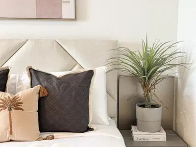 a bed with a pillow and a potted plant at Welhome - Elegant Studio with Skyline Views & Comfort in Dubai