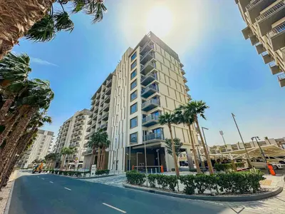 a tall building with palm trees in front of a street at Welhome - Elegant Studio with Skyline Views & Comfort in Dubai