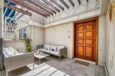 a porch with a couch and a wooden door at The Smart Concierge - Delphine in Dubai