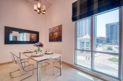 a dining room with a table and chairs and a large window at The Smart Concierge - Delphine in Dubai