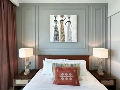 a bedroom with a bed with two lamps and three dresses on the wall at Trophy-Sunset Coral Retreat Beachfront Living in Dubai