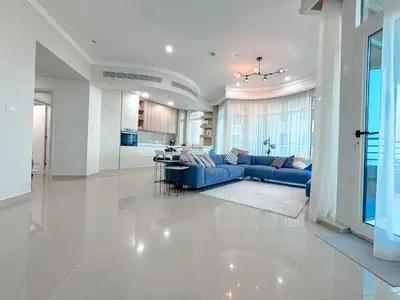 a living room with a blue couch and a kitchen at DreamShoma-Sea View 2BR Pool Gym in Dubai