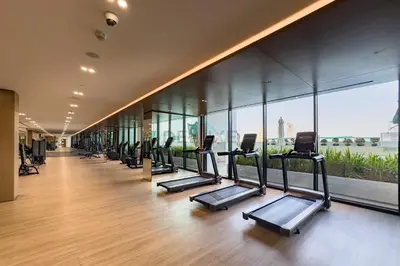 a row of treadmills in a gym with windows at Studio Near Dubai Autodrome & Trump Golf Club, Binghatti Amber, JVC By Deluxe Holiday Homes in Dubai