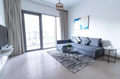a living room with a blue couch and a large window at Park Heights 2 Dubai Hills 1BR by Happy Season in Dubai