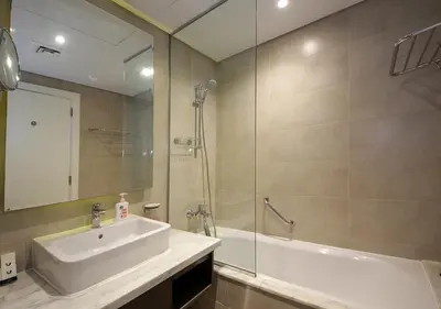 a bathroom with a sink and a shower and a tub at Dubai Dreams Pool & Canal View at Prive in Dubai