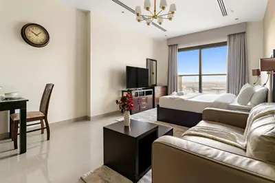 a bedroom with a bed and a living room with a desk at Cozy Studio in Downtown Dubai in Dubai