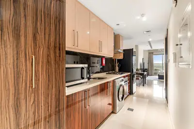a kitchen with wooden cabinets and a microwave at Cozy Studio in Downtown Dubai in Dubai