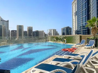 a large swimming pool with lounge chairs and a city skyline at Cozy Studio in Downtown Dubai in Dubai
