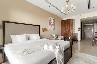 a bedroom with a large bed and a living room at Cozy Studio in Downtown Dubai in Dubai