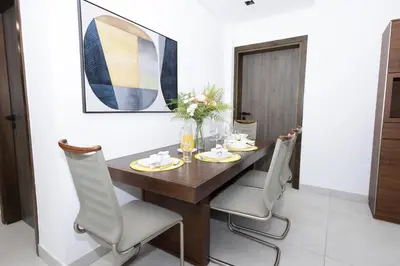 a dining room with a wooden table and chairs at Spacious 2BR Apartment l Rooftop Pool l Gym in Dubai