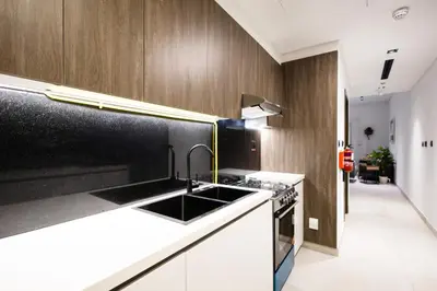 a kitchen with a sink and wooden cabinets at Spacious 2BR Apartment l Rooftop Pool l Gym in Dubai
