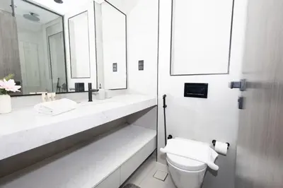 a bathroom with a toilet and two sinks and a mirror at Spacious 2BR Apartment l Rooftop Pool l Gym in Dubai