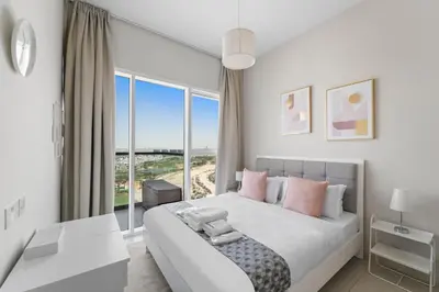 a white bedroom with a large bed with pink pillows at Modern 1BR at Golf Vita A in Damac Hills Near Golf in Dubai