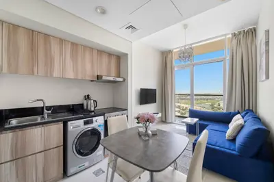 a kitchen and living room with a table and a blue couch at Modern 1BR at Golf Vita A in Damac Hills Near Golf in Dubai
